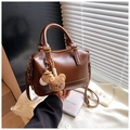 Detail of a brown leather handbag with cute plush bear charms on a white blazer background - With Charm Style / Brown with Pendant