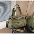 Detail of olive green nylon tote bag with adjustable strap in natural light setting - Green