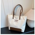 Detail of white corduroy tote bag featuring brown leather straps and printed text - White