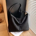 Minimalist large black suede hobo bag with adjustable leather strap in a lifestyle setting - Black