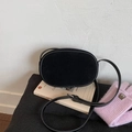 Dettaglio di una borsa a tracolla ovale in camoscio nero minimalista sui libri - Nero