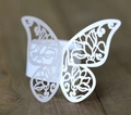 Detailed macro view of laser-cut white paper butterfly napkin ring with floral patterns - White