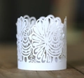 Detailed close-up of white laser-cut paper decorative sleeves with intricate floral patterns - White