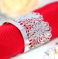 Servilletero de plata pulida calado con diseño floral sobre una servilleta roja - Plata Reflectante