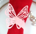 Pink laser-cut butterfly paper napkin ring shown on a red fabric for wedding table decor - Pink