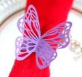 Gros plan du rond de serviette papillon violet nacré sur une serviette en tissu rouge - Violet foncé