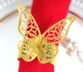 Golden butterfly napkin ring with laser-cut hollow design on a festive red cloth napkin - Reflective Gold