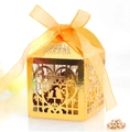 Dettaglio della scatola regalo dorata tagliata al laser con motivo di uccelli e nastro arancione - Oro Riflettente