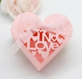 Draufsicht auf rosa herzförmige Geschenkschachtel mit lasergeschnittenem IN LOVE Design - Rosa