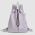 Detail of lavender drawstring backpack showing waterproof nylon fabric and brand label - Purple