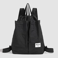Detail of black nylon drawstring backpack featuring top handles and side pockets - Black