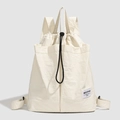 Close-up of the textured nylon fabric and drawstring closure on the off-white backpack - Beige