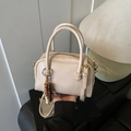 Beige Boston bowling bag with dual handles and beaded charm in a lifestyle interior - With Charm / Off White