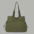 Close-up of army green nylon tote bag with side drawstrings and metal snap closure detail - Green