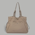Detailed close-up of water-resistant nylon tote bag with front pocket and side drawstrings - Khaki