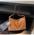 Detail of a large brown suede tote bag with a plush charm on a wooden shelf - Brown with Pendant