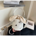 Detail of white bucket bag featuring silver metal butterfly charms and beige drawstring - Off-white