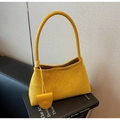 Detail of yellow suede underarm bag with matching leather tag on vintage books - Yellow
