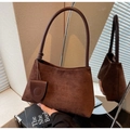 Close-up of deep brown suede tote bag featuring a round charm and textured shoulder strap - Coffee