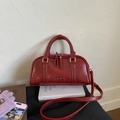 Nahaufnahme der roten Vintage Leder Boston Tasche mit Metalllogo und Schultergurt - Rot