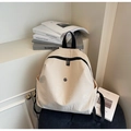 Detail of beige canvas backpack showing black straps and metal logo on textured surface - Off-white