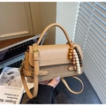 Dettaglio di una borsa quadrata vintage marrone con nappa di perline di legno su sfondo - Cachi (Con Ciondolo)
