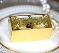 Macro view of golden cutout Christmas gift box with snowflake design and engraved text - Reflective Gold