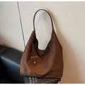 Detalle del bolso hobo de ante marrón oscuro con una forma de media luna minimalista - café