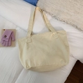 Close-up of beige canvas tote bag on white bedding with purple knit gloves accessory - Off-white