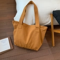 Vista de las costuras reforzadas en el asa del bolso tote de lona amarillo mostaza y textura - Naranja