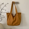 Detail of a large amber canvas tote bag with wide straps in a minimalist aesthetic - Orange