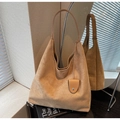 Primer plano de bolso tote de ante caqui con colgante ovalado de metal y asas finas - Caqui