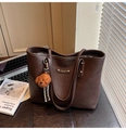 Detalle de bolso tote marrón oscuro con piel texturizada y un colgante de oso peludo - Café con Colgante