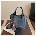 Détail du sac seau texturé gris avec breloque ours et logo fashion gravé sur le sac - Noir avec pendentif