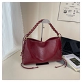 Detail of burgundy leather shoulder bag showing woven handle and metallic eyelet accents - Red