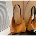 Close-up of caramel suede hobo bag featuring vertical seam detail and dark leather strap - Brown
