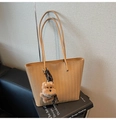 Detail of tan woven tote bag with herringbone texture and a brown plush puppy charm - Khaki