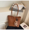 Detail view of brown woven tote bag with V-shaped texture and plush bear pendant - Brown