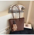 Detail of dark brown woven tote bag featuring a plush teddy bear with pearl necklace - Brown