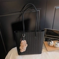 Black woven tote bag with brown plush bear charm and pearls on a sleek desk setup - Black