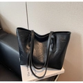 Detail of vintage black pleated tote bag with double straps on a leather chair - Black