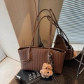 Brown woven tote bag with puppy charm and striped scarf shown on wooden surface - Coffee