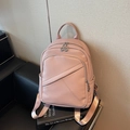 Rosa Lederrucksack mit Kieselstruktur und Reißverschlüssen auf schwarzem Sofa - Rosa