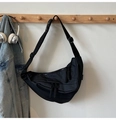 Dettaglio borsa a tracolla nera in nylon a mezzaluna appesa a un gancio con cuffie vicine - Nero Grande