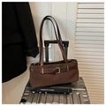 Détail du sac bandoulière en daim marron avec boucle argentée vintage sur une valise - Marron