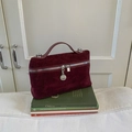 Sac à main vintage en daim bordeaux avec finitions argentées posé sur des livres - Rouge