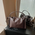 Detailansicht der dunkelbraunen Ledertasche mit elegantem Faltendesign und geknoteten Henkeln - Braun