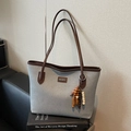 Grand sac cabas en tissu gris avec garniture en cuir marron et pendentif sur un canapé - Bleu