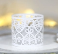 Detail view of laser-cut white heart napkin rings with elegant floral hollow patterns - White