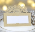 Détail du marque-place doré découpé au laser avec motif dentelle sur une assiette blanche - Papier kraft